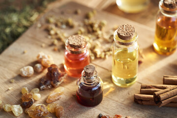 Several bottles of aromatherapy essential oil with frankincense resin and dried medicinal plants