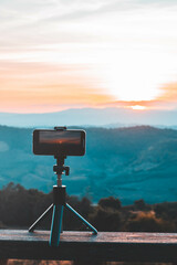 A smartphone is recording the sun setting over a mountain range.