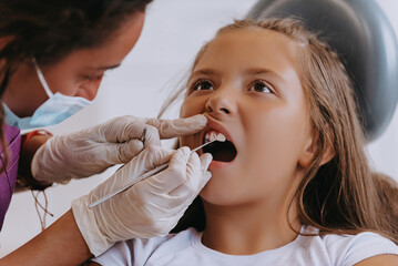 A cheerful girl undergoes a dental examination in a modern pediatric dentistry clinic