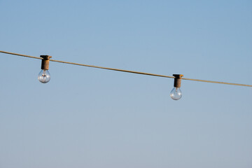 Duo von Lampen - ein Paar Outdoor Glühbirnen an einem Stromkabel gegen den Himmel