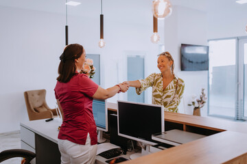 Beautiful blonde shakes hands with an employee of the dental office after the agreed dental...