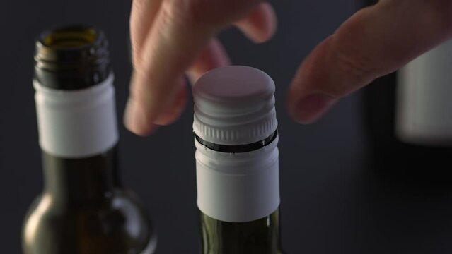 Opens a bottle with a screw cap. Close-up, shallow dof.