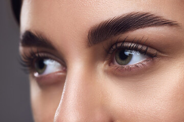 Close-up of a woman's eyes with well-defined eyebrows, full lashes, and smooth skin, highlighting...