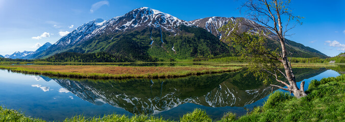 Fototapeta na wymiar Tern Lake along Seward Highway on Kenai Peninsula in Alaska. At junction with Sterling Highway in Chugach National Forest. Mountain landscape perfectly reflected in mirror still alpine lake.