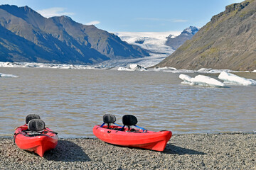 Kayaks on the gravel beach of a glacial lake, Iceland, ready for adventurers.