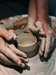 couple making a bowl in a pottery wheel