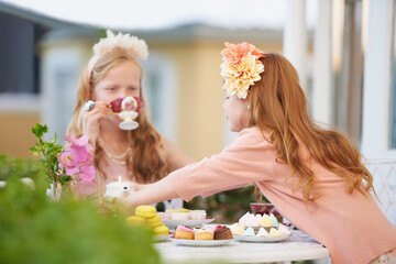 Girls, children and friends at tea party outdoor for fantasy play in garden for cake, birthday or...