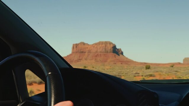 Beautiful in-car view, driving down an atmospheric desert mountain road at sunny summer Monuments Valley in Arizona.