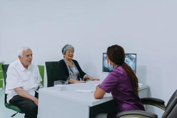 An elderly couple engages in a thoughtful discussion with their dentist about modern denture options in a contemporary dental office setting