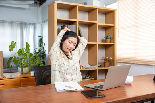 oung Asia girl development programmer overwork relax stretch muscle painful from office syndrome solve problem coding program fix database on computer on table in workplace at house office.
