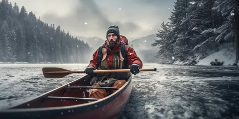 Foto op Canvas Rafting of a male tourist in a wooden canoe on a river with winter forest on either side. © OleksandrZastrozhnov