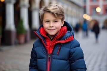 Portrait of a smiling boy in a blue down jacket on the street