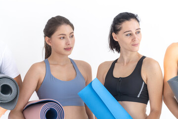 Group of happy sporty women and guy wearing body stylish sportswear holding personal carpets leaned on a white background. waiting for yoga class or body weight class. healthy lifestyle and wellness