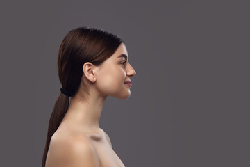Side view of young brunette woman with ponytail and bare shoulders, doing exercises for prevent...
