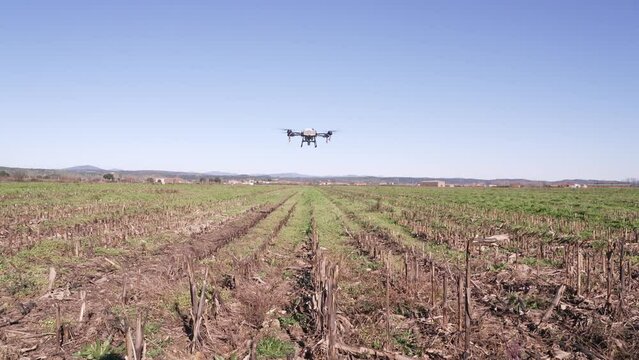 Detalle de un drone de agricultura fumigando un campo de cultivo.