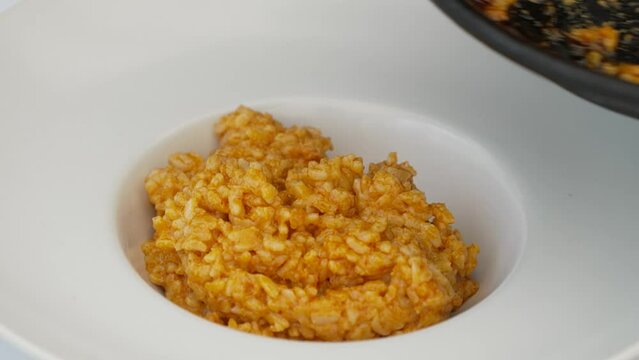 La mano de una cocinera emplatando una receta de arroz.