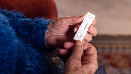 Close-up of grandma hand holding a positive buffer dropper of coronavirus