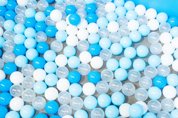 Colored plastic balls in pool of kindergarten school,White and blue plastic balls pit in game room,Many white balls background.