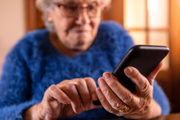 Elderly woman using a mobile phone over wood table at living room of home.
