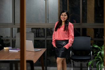 portrait of a latin business woman standing in her office looking at the camera smiling