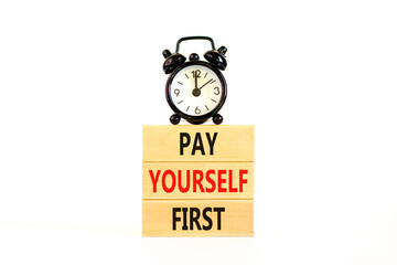 Pay yourself first symbol. Concept words Pay yourself first on beautiful wooden blocks. Beautiful white table white background. Black alarm clock. Business and pay yourself first concept. Copy space.