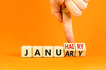 Januhairy or January symbol. Concept words Januhairy or January on beautiful wooden blocks. Beautiful orange table orange background. Man hand. Social issues Januhairy or January concept. Copy space.