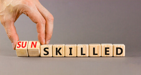 Sun skilled symbol. Concept words Skilled or Sun skilled on beautiful wooden blocks. Beautiful grey table grey background. Businessman hand. Business sun skilled concept. Copy space.