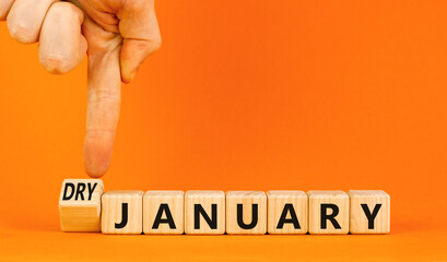 Dry January challenge symbol. Concept words Dry January on beautiful wooden cubes. Beautiful orange table orange background. Businessman hand. Dry January healthy lifestyle concept. Copy space.