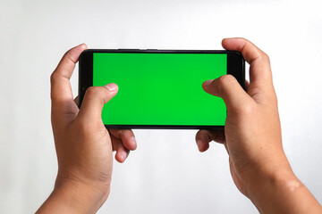 closeup of hands holding smart phones with green screen and showing playing game isolated on white background