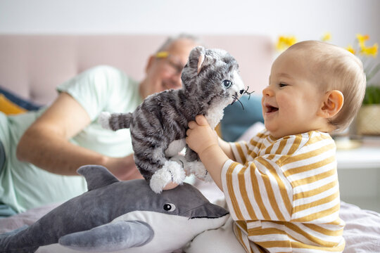 Joyful Toddler Playing With Plush Toys At Home