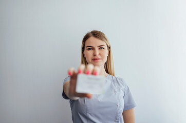 Young woman beautician in gray uniform holds box with skin care produc