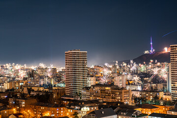 A vibrant display of fireworks bursting over the night sky of Tbilisi, lighting up the cityscape with various colors and patterns
