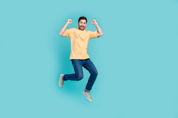 Fototapeta na wymiar Full length photo of jumping trampoline air young guy in casual outfit raised fists up crazy football fan isolated on cyan color background