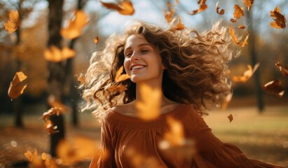 Joyful smiling woman throwing leaves into the air in the park in autumn. autumn theme orange color