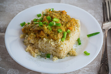 cooked bulgur with meat sauce and vegetables in a plate