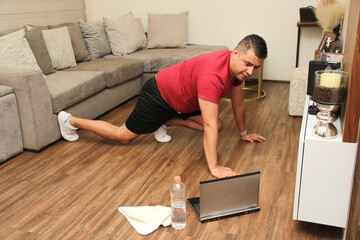 40-year-old dark-skinned Latino man does push-ups, plank to strengthen arms and legs in...