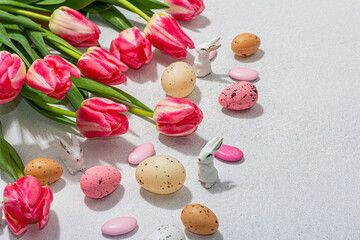 Pink tulips with Easter eggs on light stone concrete background. Festive concept, greeting card