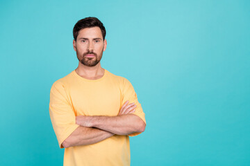 Fototapeta premium Portrait of young confident guy in yellow t shirt folded hands seems like experienced ceo product owner isolated on cyan color background