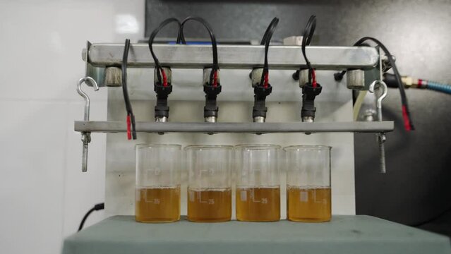 Automotive ultrasonic fuel injector cleaning system in operation at auto repair shop. Precision cleaning tech restores injector efficiency, vital for engine performance, fuel economy.
