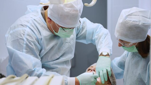Installation of dental implants in modern dental clinic. Oral surgeon and nurse during operation in the medical clinic. Dental implant surgery. Dentist and assistant during teamwork. Close-up.