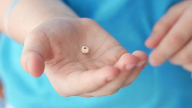 A baby tooth that fell out naturally lies on the child's open palm. Preserves baby teeth.