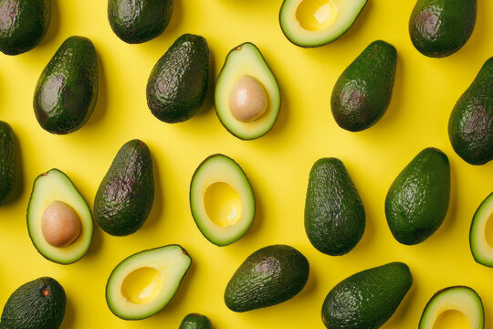 Many cut avocados on a yellow surface, pattern seamless, flatlay layout. Concept of healthy food, diet