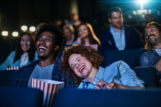 Young couple sharing popcorn during a movie in cinema