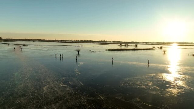 Ice skating on the floodplains of the Zwarte Water near Hasselt in nature seen from above during a cold winter day in The Netherlands.