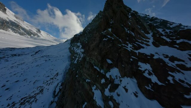 FPV drone flying over tall mountains sunny weather shadow side pov birdview mountains snow alps