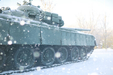 Military tank in a row. Battle tank in the snow on the roadside of highway. War in Ukraine in winter.