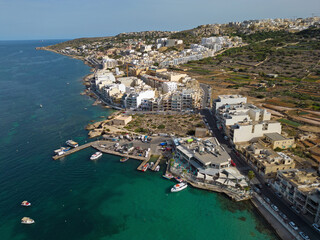 Beautiful Mellieha town settled by the sea and the hills in Malta. Aerial view of the Malta coastline with town harbor.