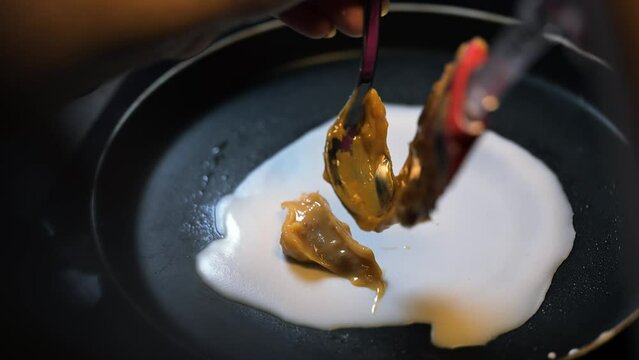 Closeup of making steaming hot crepe layer on a cast iron pan. A thin pancake made with rice flour dough and condensed milk stuffing. Thin batter being spread and cooked for making 'Pithe' and 'dosa'