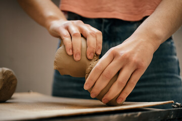 The ceramist s hands tear and divide soft, raw white clay into pieces. Preparing for clay modeling...