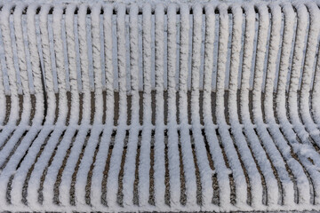 Gennevilliers, France - 12 18 2024: Eco-neighborhood. View of a metallic bench covered in snow in a park .
